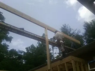 Carpenter setting a ridge beam over a new addition frame — Ice Dam Removal by Roofing Brothers in Eads