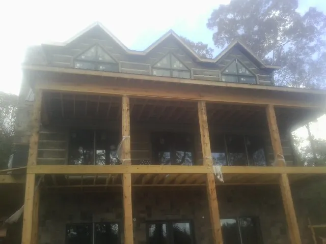 Dormers and porch framing on a large log home under construction — Roof Coating work by our crew in Eads