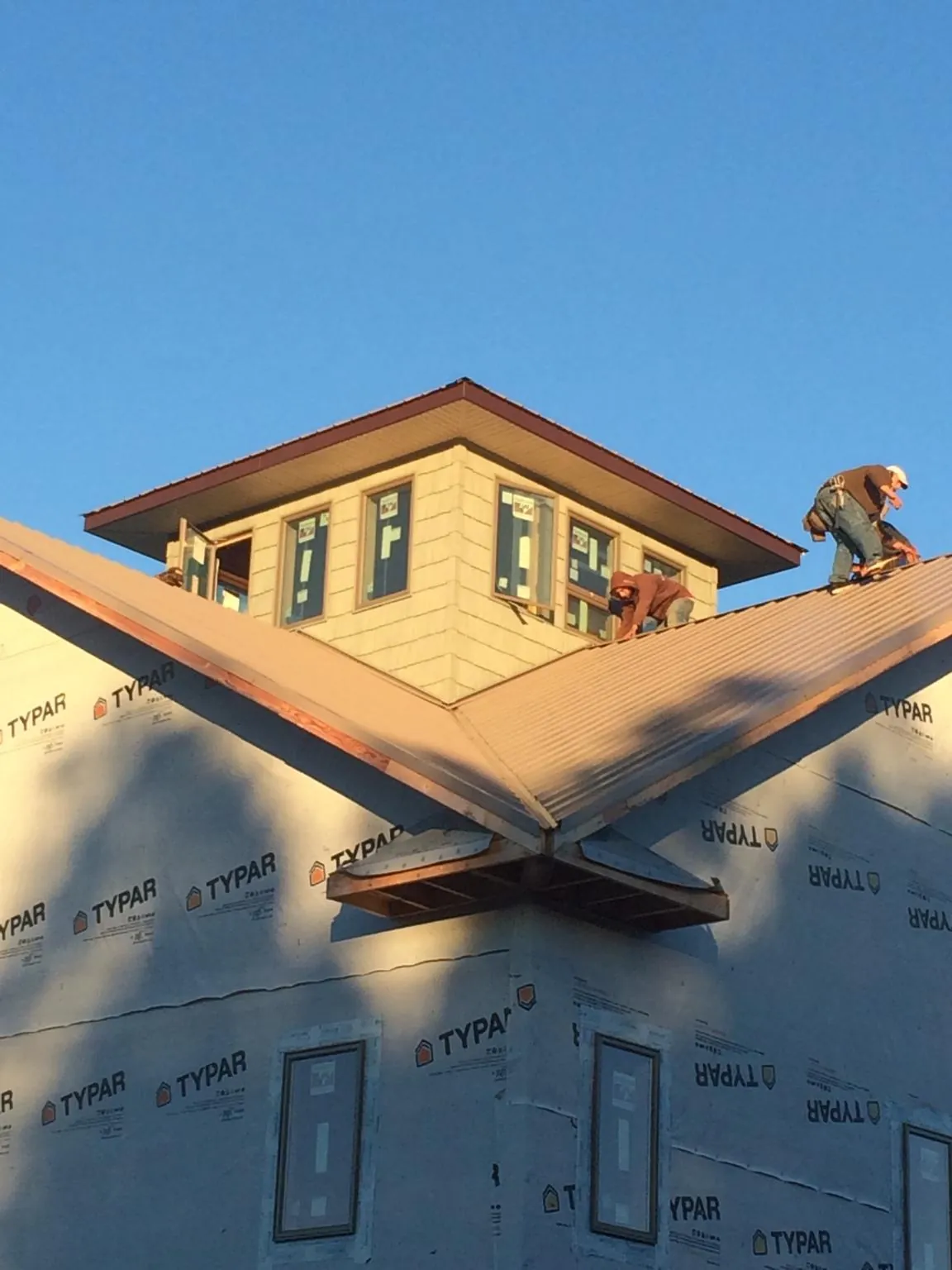 Roofers working around a rooftop cupola on a new metal roof at sunset — Roof Waterproofing in Eads by Roofing Brothers
